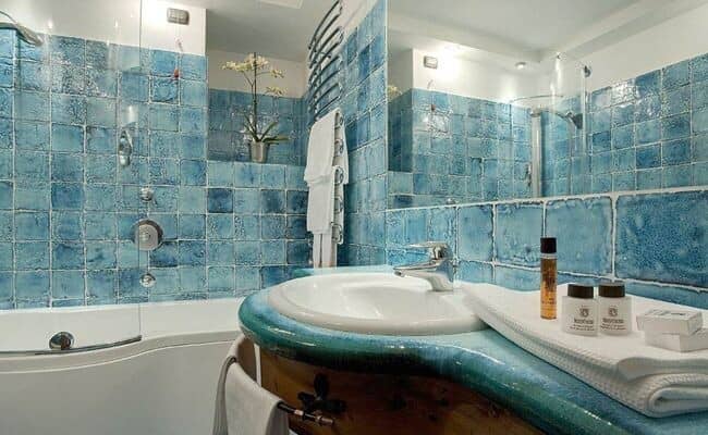Bathroom featuring handmade blue tile, soaking tub, and heated towel rack