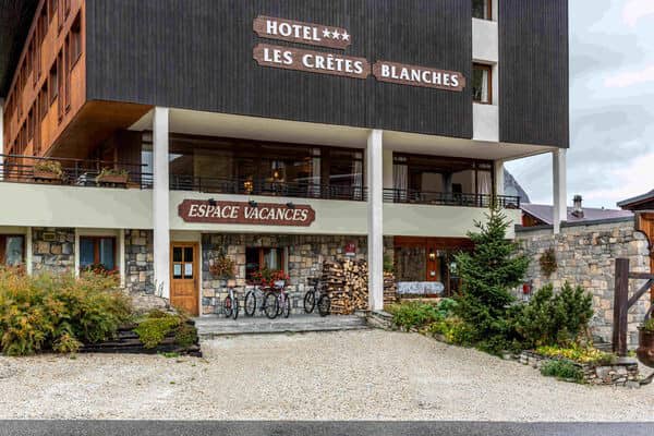 Hotel entrance with stone facade, gravel parking, and bicycle storage area