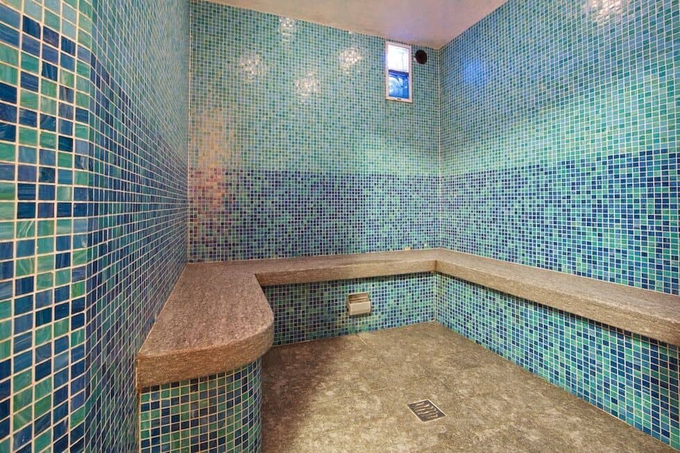 Private steam room with mosaic tile and stone bench seating