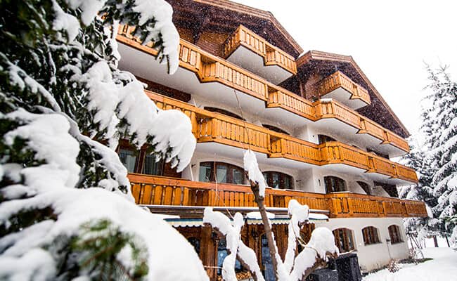 Chalet exterior with multiple private balconies and snow-covered pine trees