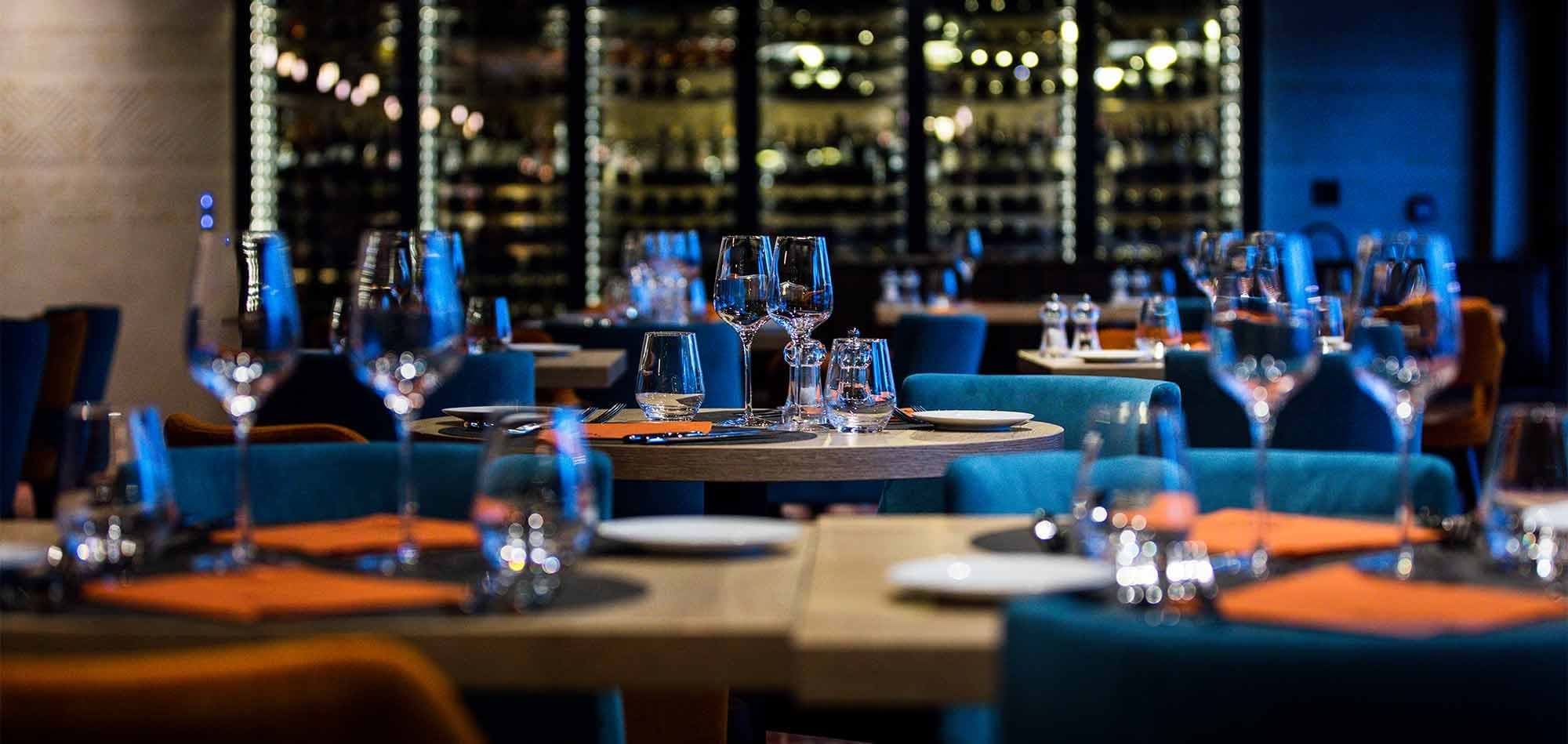 Dining room with circular tables and glass-walled wine cellar