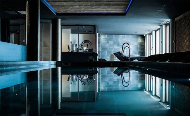 Indoor heated pool with adjacent gym and poolside loungers