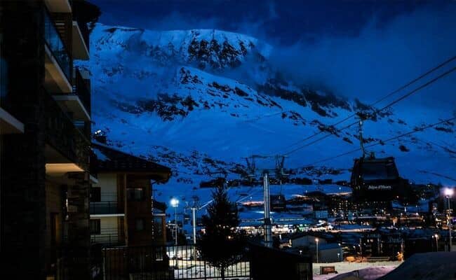 Balcony view of Alpe d'Huez ski lifts and illuminated mountain peaks