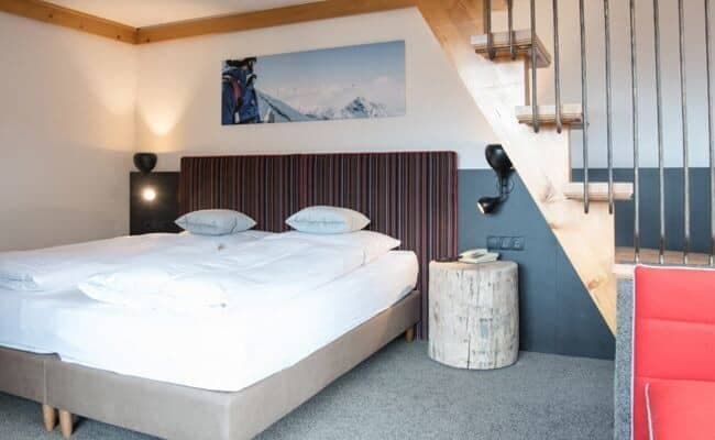 Bedroom with king bed tucked under open staircase