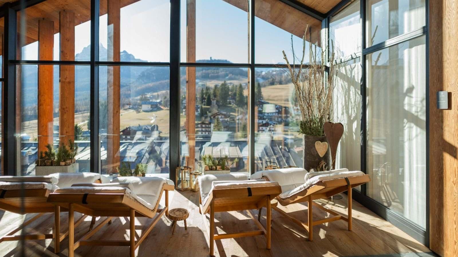 Sunroom with four wooden lounge chairs and floor-to-ceiling mountain views