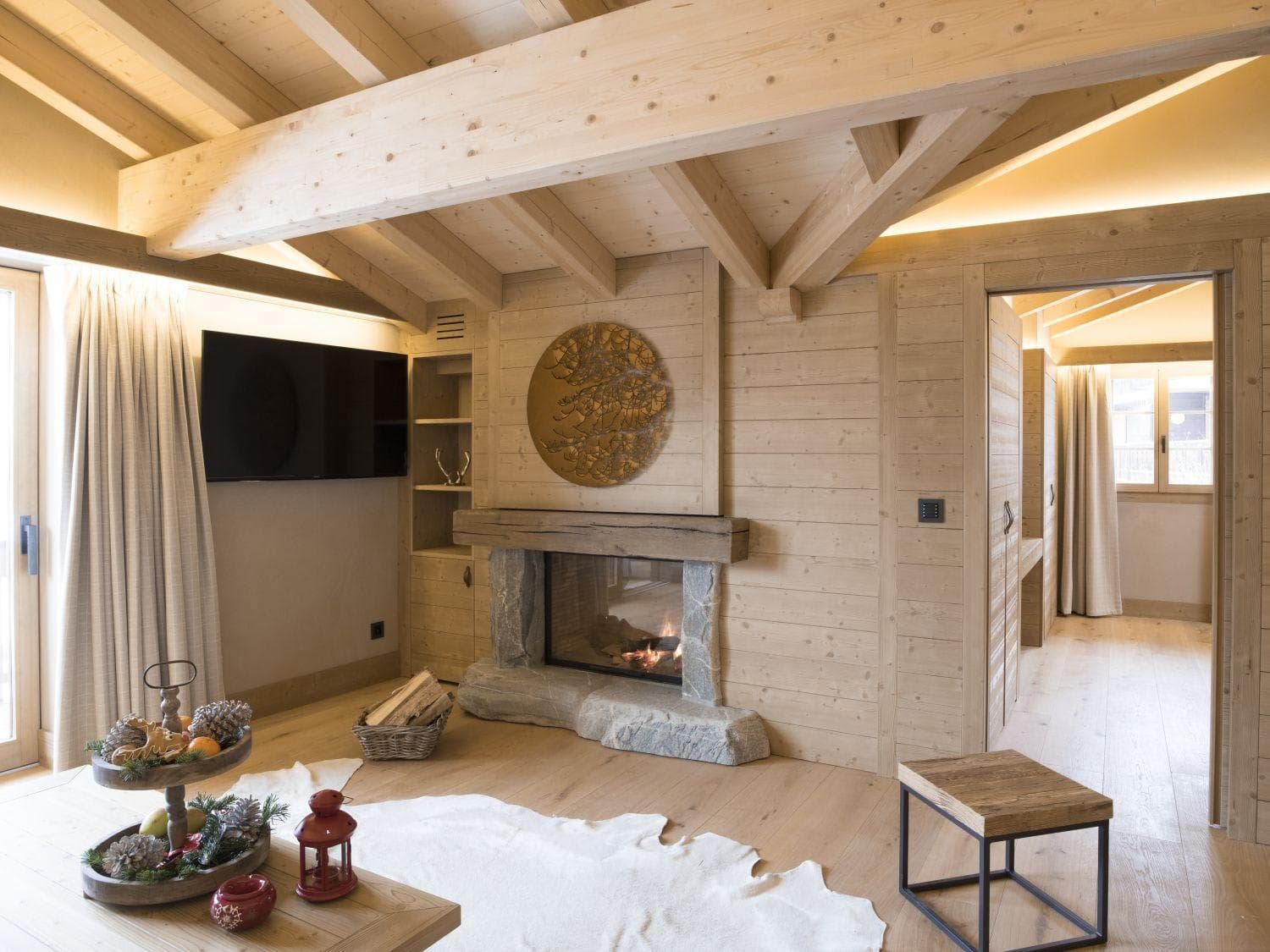 Living area with wood-burning stone fireplace and vaulted timber ceilings