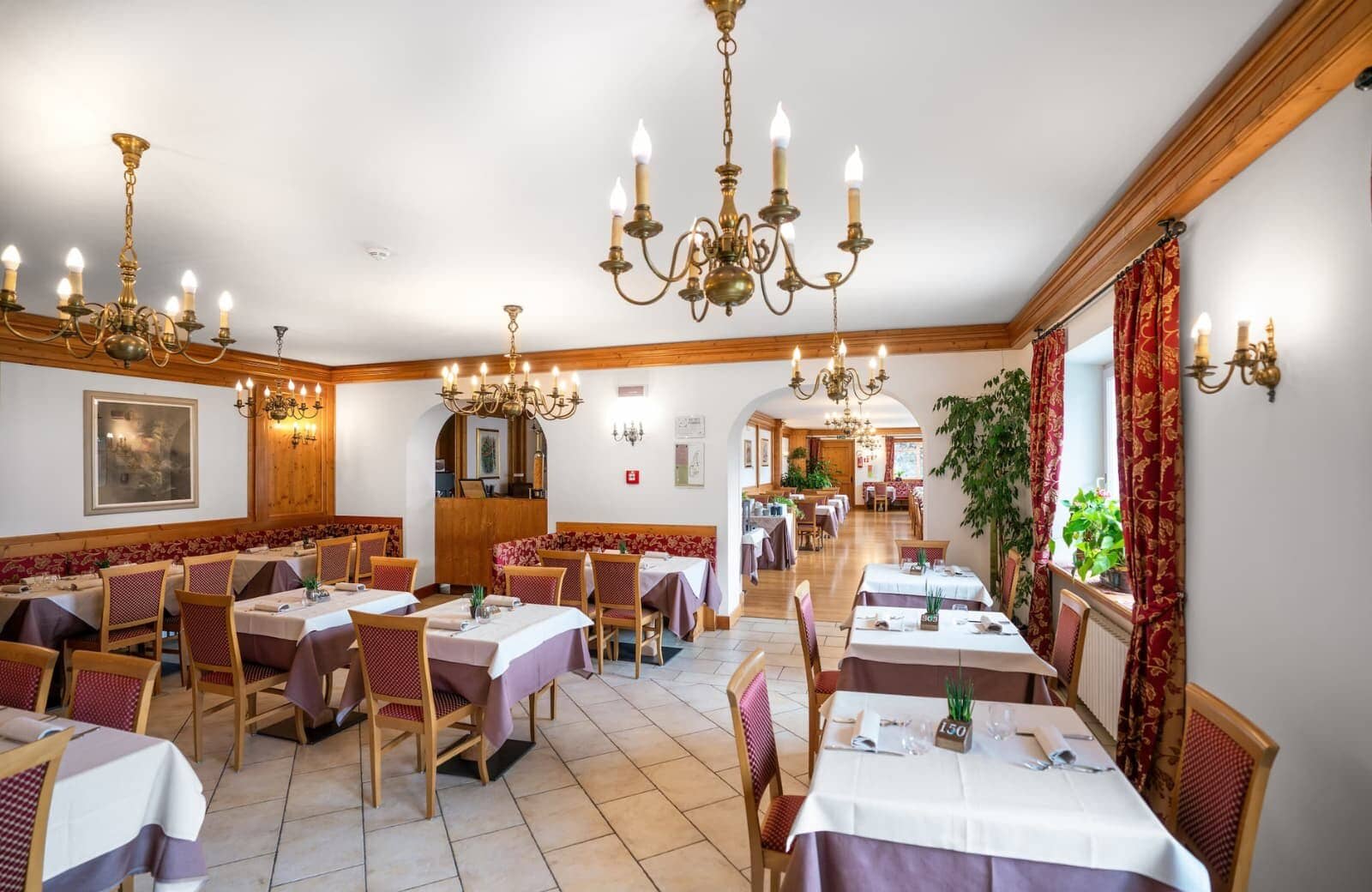 Shared dining room with brass chandeliers and seating for over 30 guests
