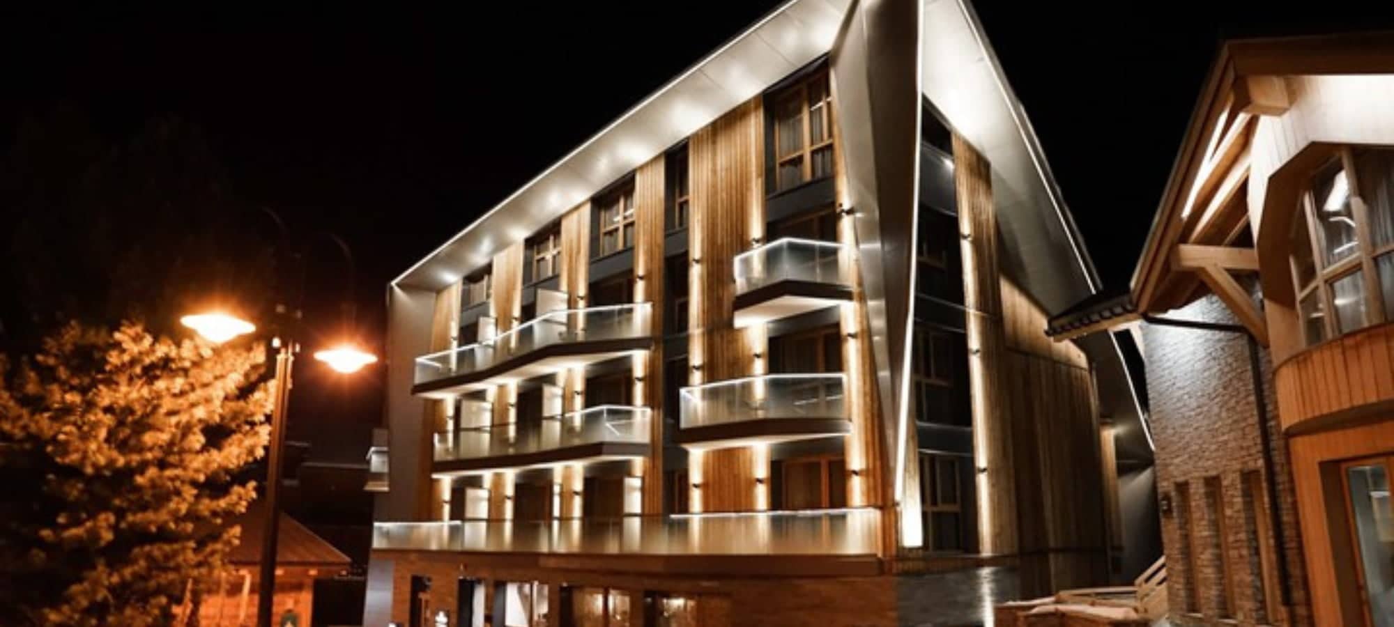 Multi-story building exterior featuring private glass-railing balconies and wood paneling