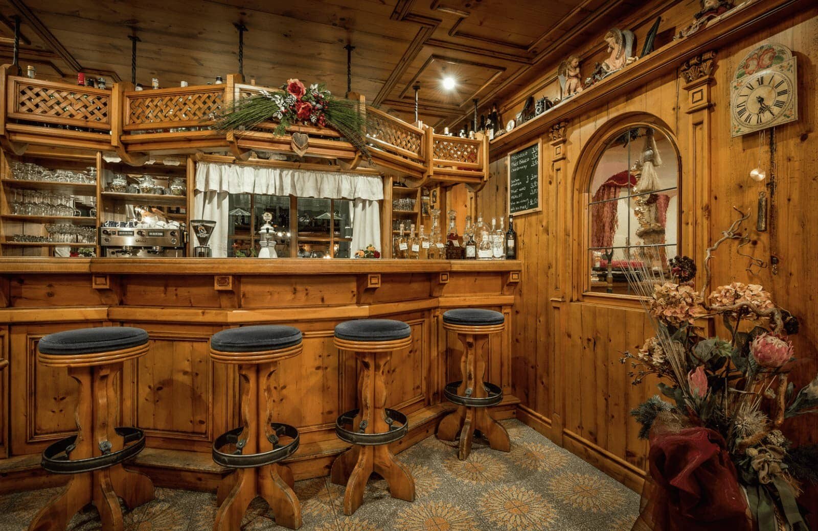 Wood-paneled wet bar with four stools and espresso machine