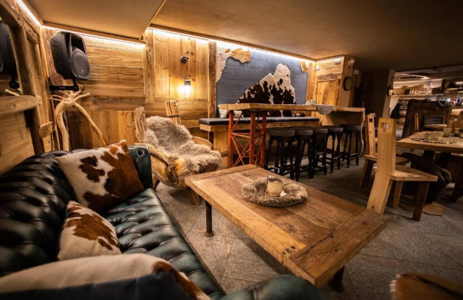 Entertainment lounge with leather seating, bar area, and wall-mounted speakers