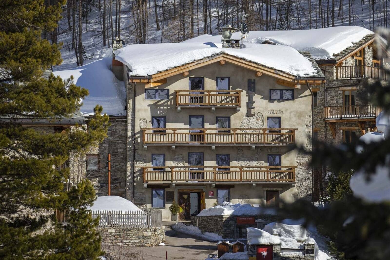 Stone and timber exterior with multiple private balconies and slope-side access