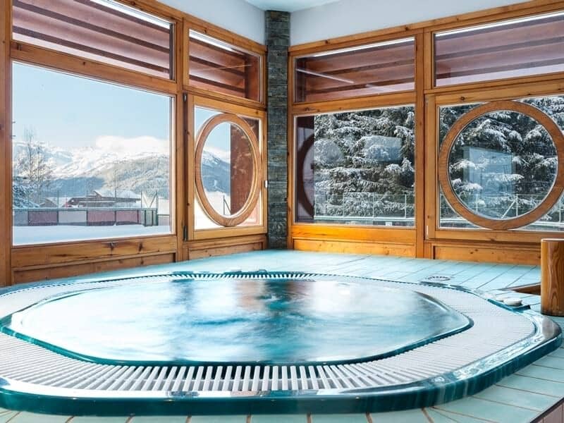 Indoor hot tub with floor-to-ceiling windows and mountain views