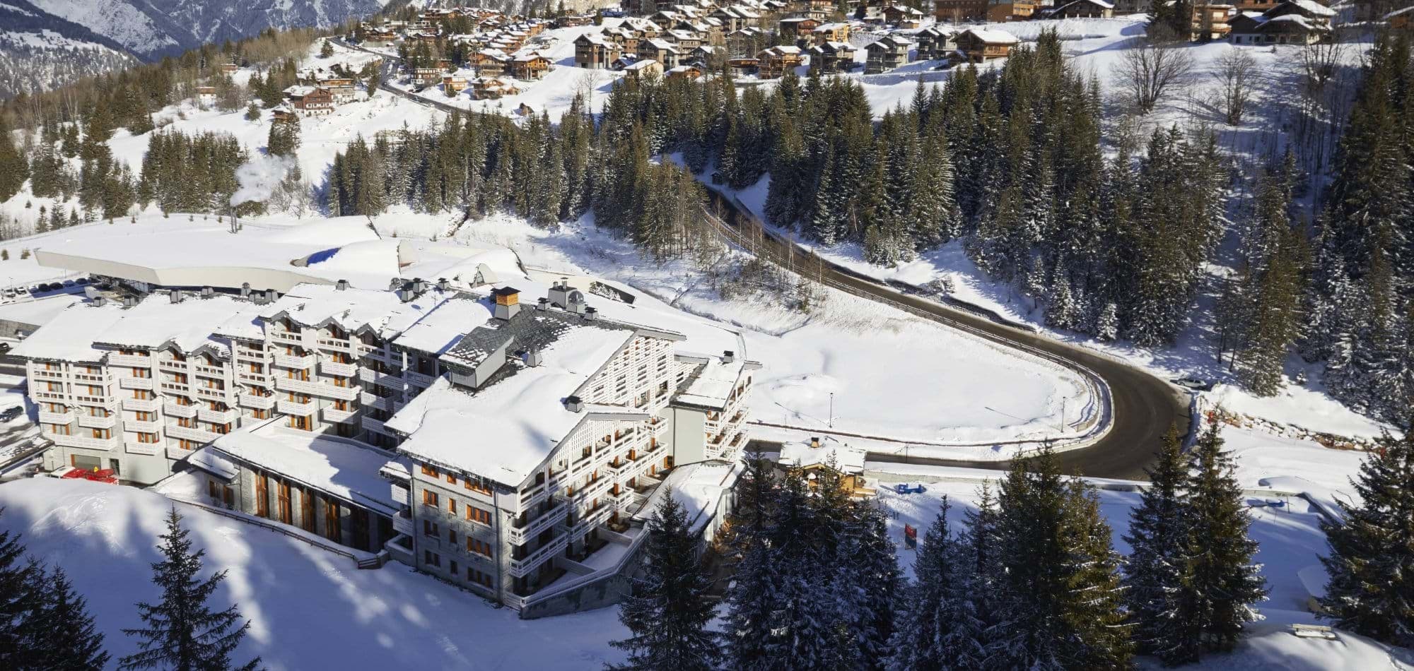 Aerial view of resort complex with private balconies and mountain backdrop