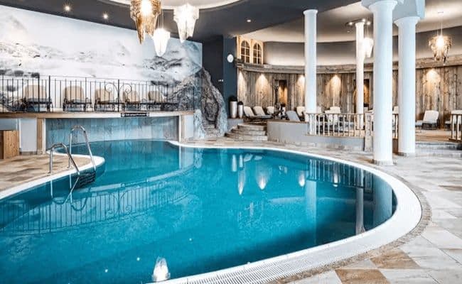 Indoor heated pool with surrounding lounge seating and mountain mural
