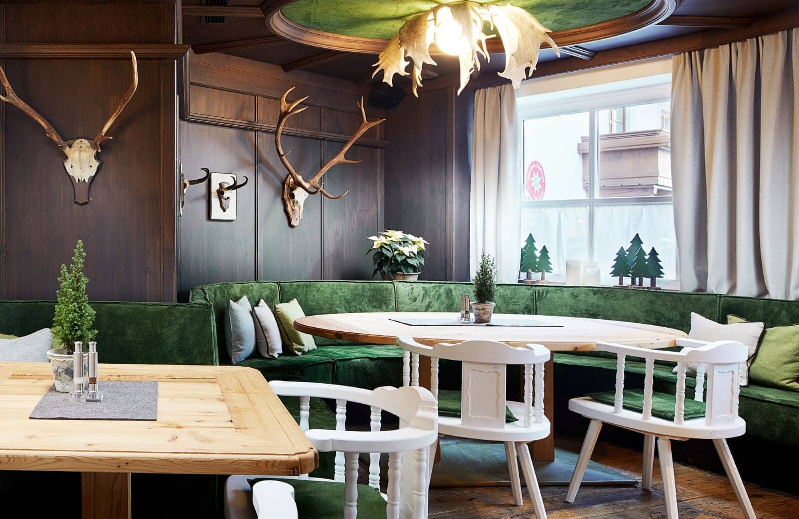 Dining area with velvet booth seating and antler chandelier
