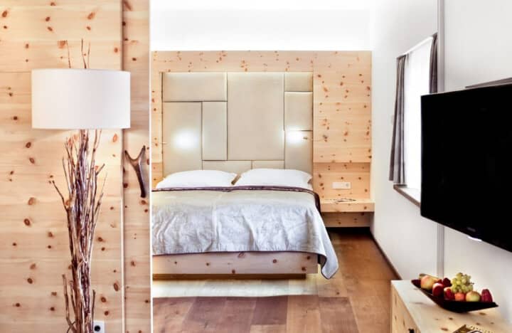 Bedroom with queen bed, knotty pine paneling, and wall-mounted TV
