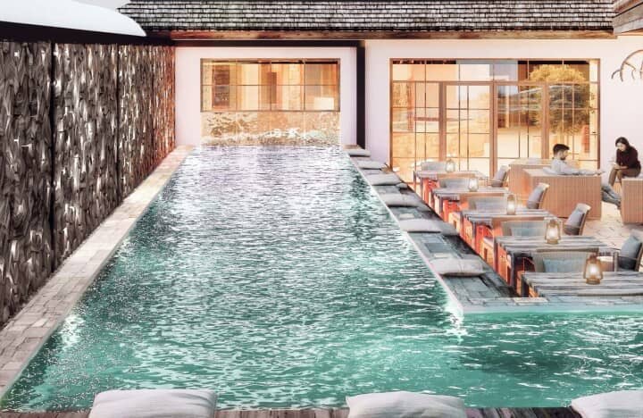 Outdoor lap pool with lounge seating and adjacent cafe area