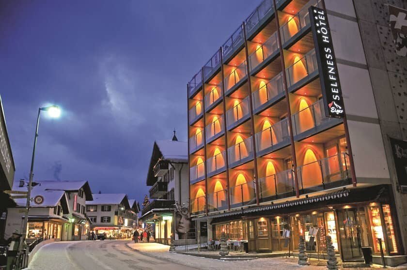 Hotel exterior featuring private glass balconies and ground-floor dining area