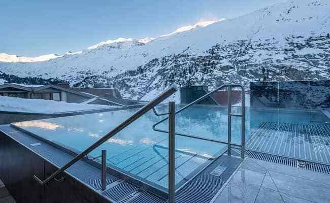 Heated infinity pool with glass safety rail and alpine mountain views