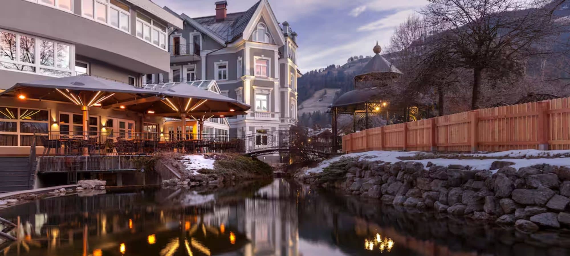 Heated outdoor terrace with dining tables overlooking garden pond and gazebo