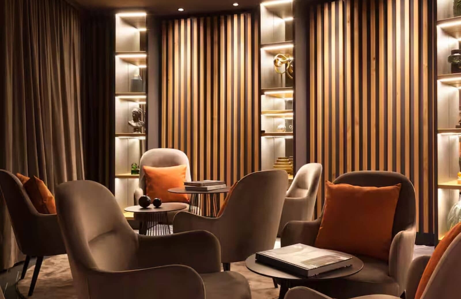 Lounge area with velvet armchair seating and backlit built-in shelving