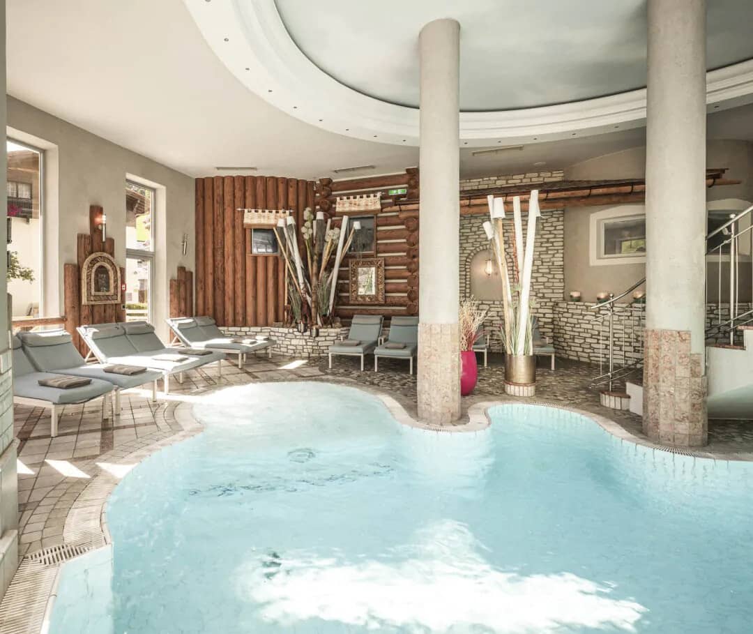 Indoor pool area with loungers and stone-tiled spa section