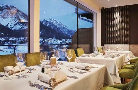 Dining area with floor-to-ceiling windows overlooking the mountain village