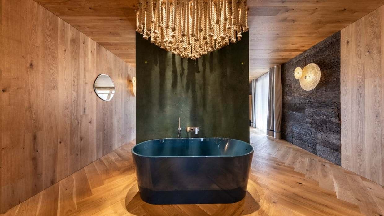 Primary suite with freestanding soaking tub and herringbone wood floors