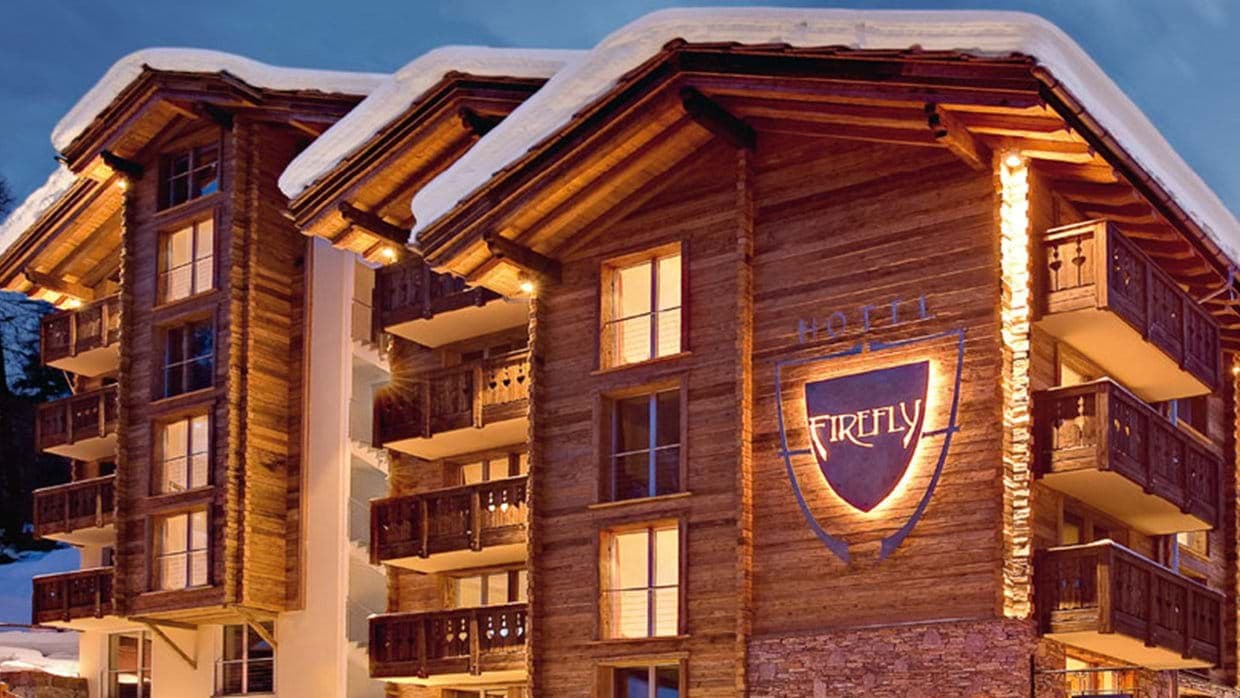 Chalet exterior with private balconies and snow-covered roof at twilight
