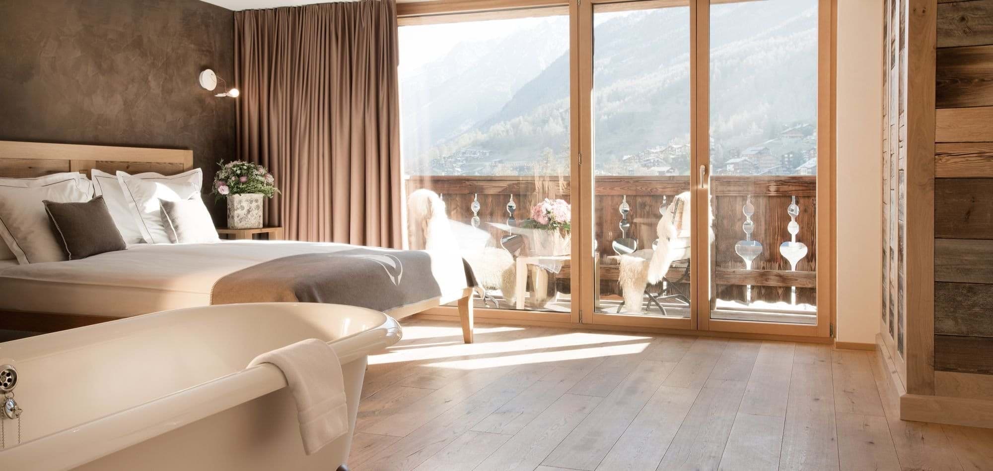 Primary bedroom with freestanding bathtub and private mountain-view balcony