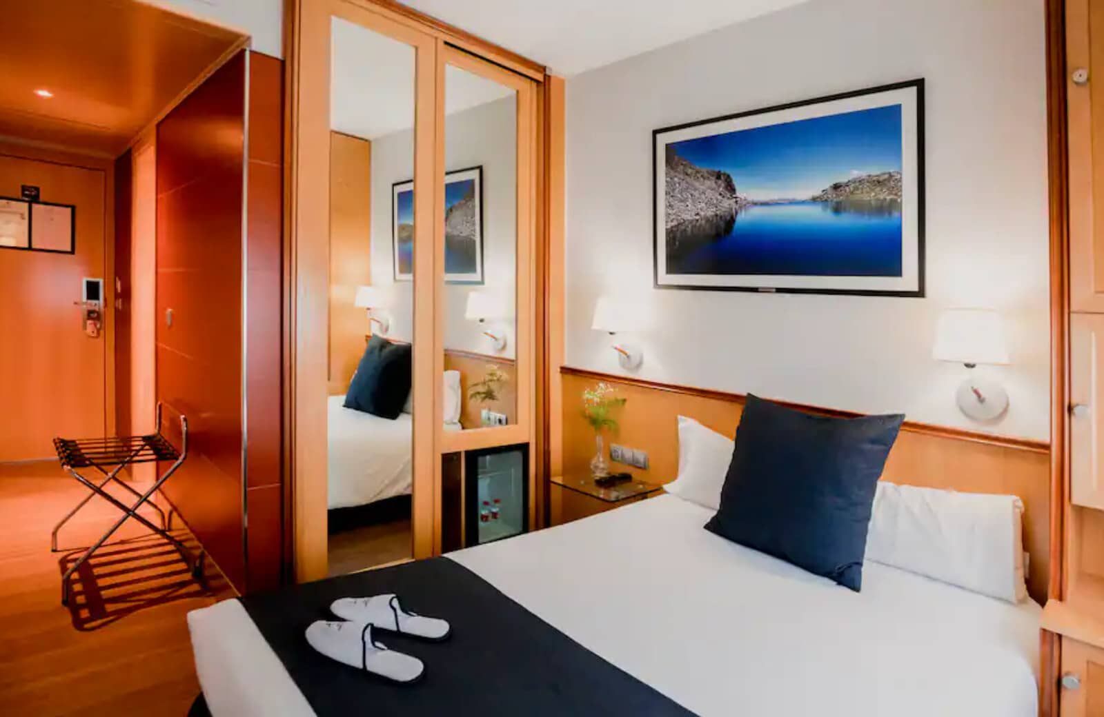 Guest bedroom with queen bed and mirrored wardrobe; folding luggage rack