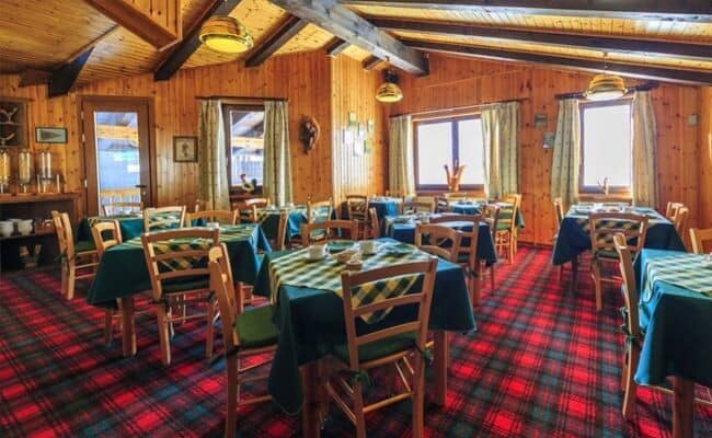 Dining room with knotty pine walls and seating for 25+ guests