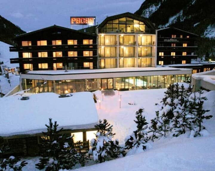 Ski-in exterior with glass-walled indoor pool and snow-covered terrace