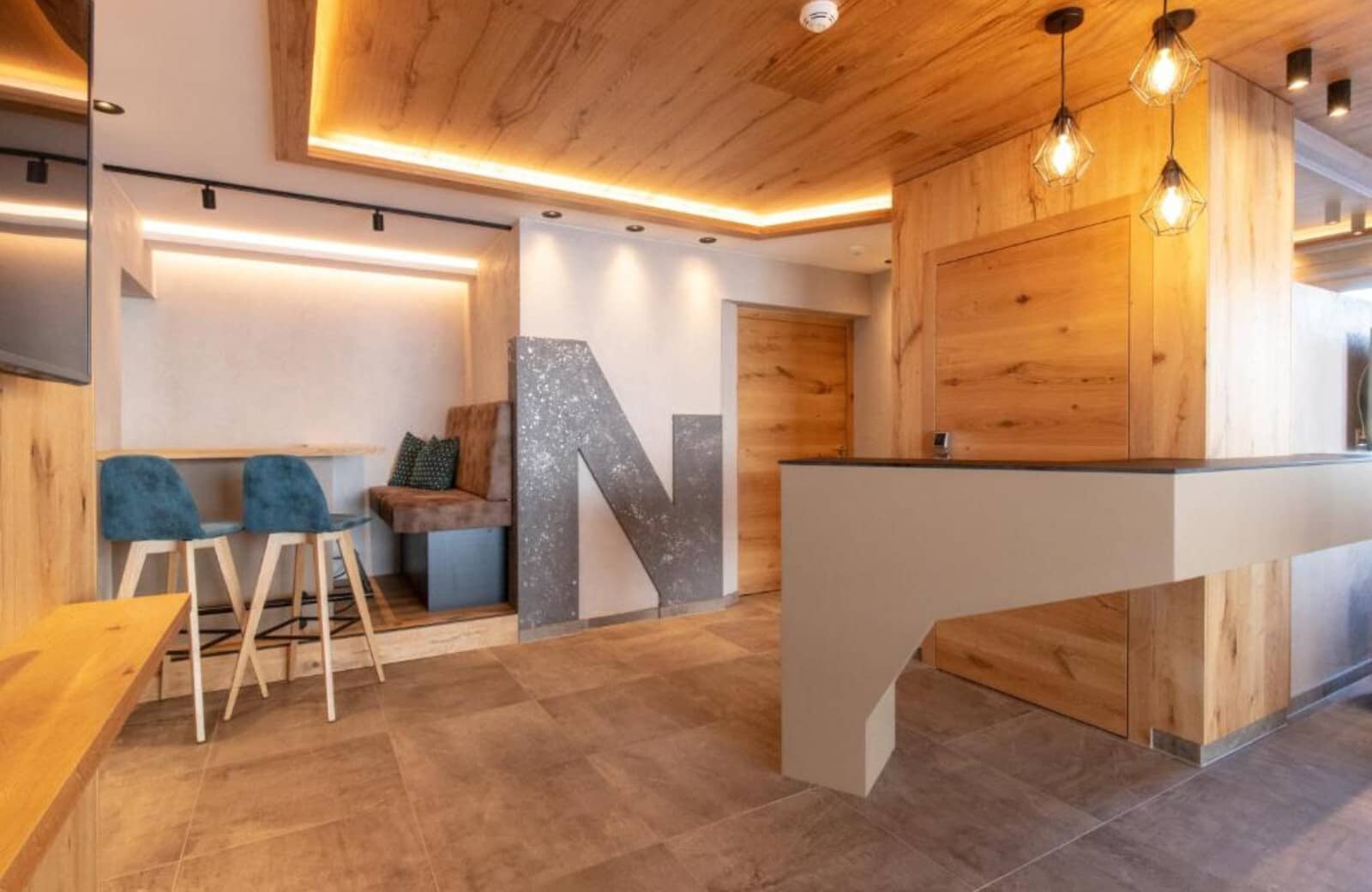 Lobby entrance with reception desk, bench seating, and high-top bar stools
