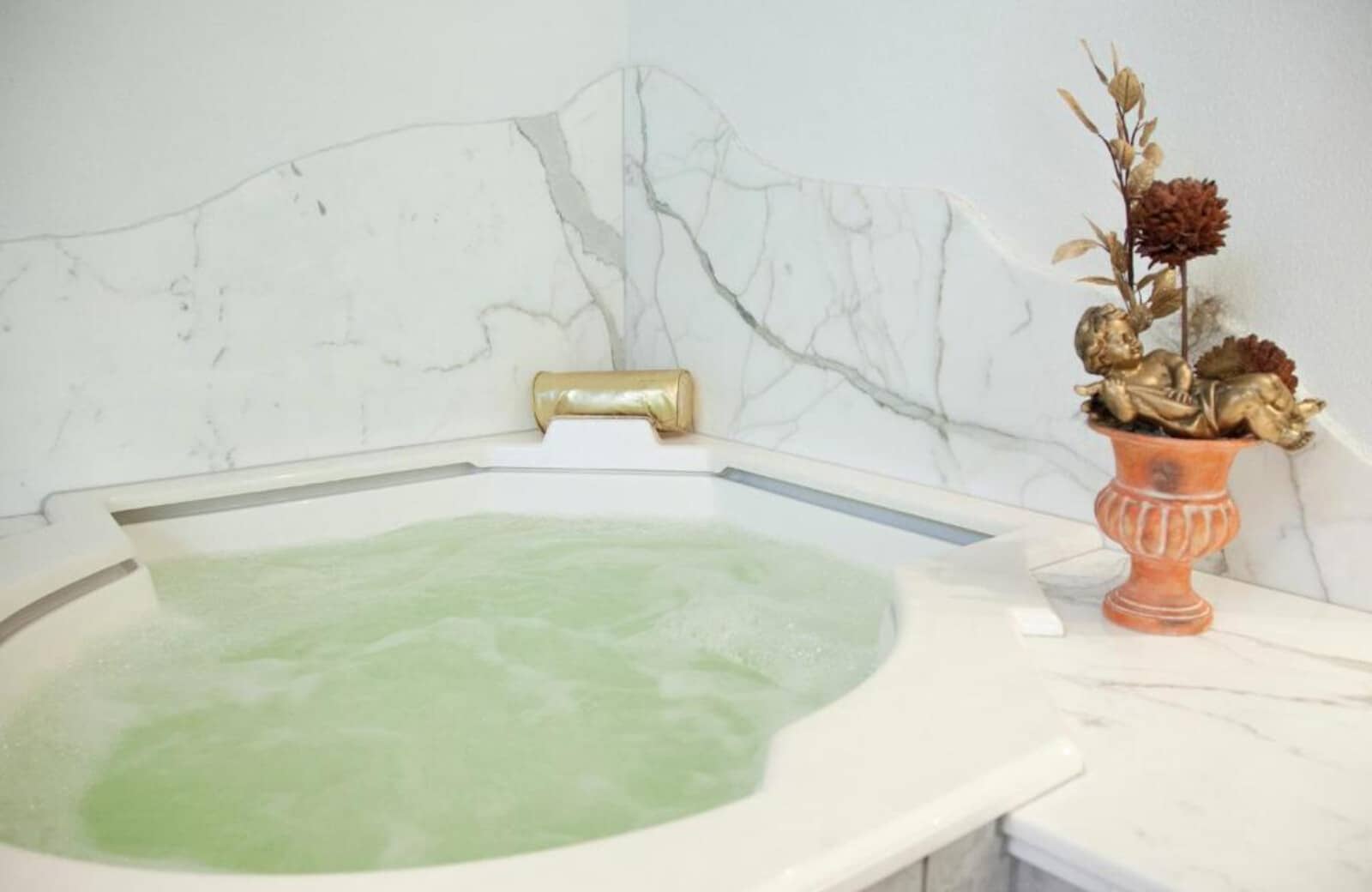 Jetted soaking tub with marble surround and gold accents