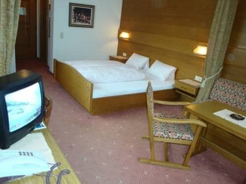 Guest bedroom with king bed, wood-paneled walls, and desk area