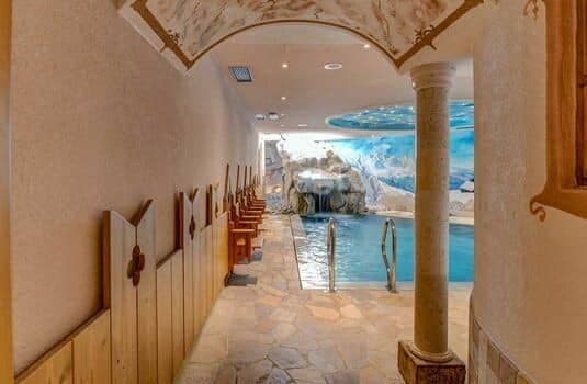 Indoor pool with stone waterfall and mountain mural backdrop