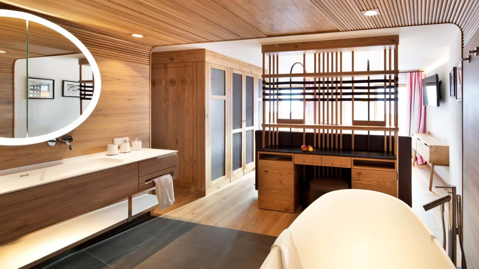 Open-concept ensuite with soaking tub and backlit vanity mirror