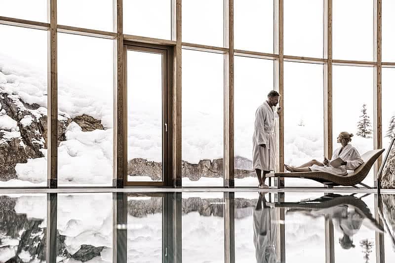 Indoor pool with floor-to-ceiling glass and snowy mountain views
