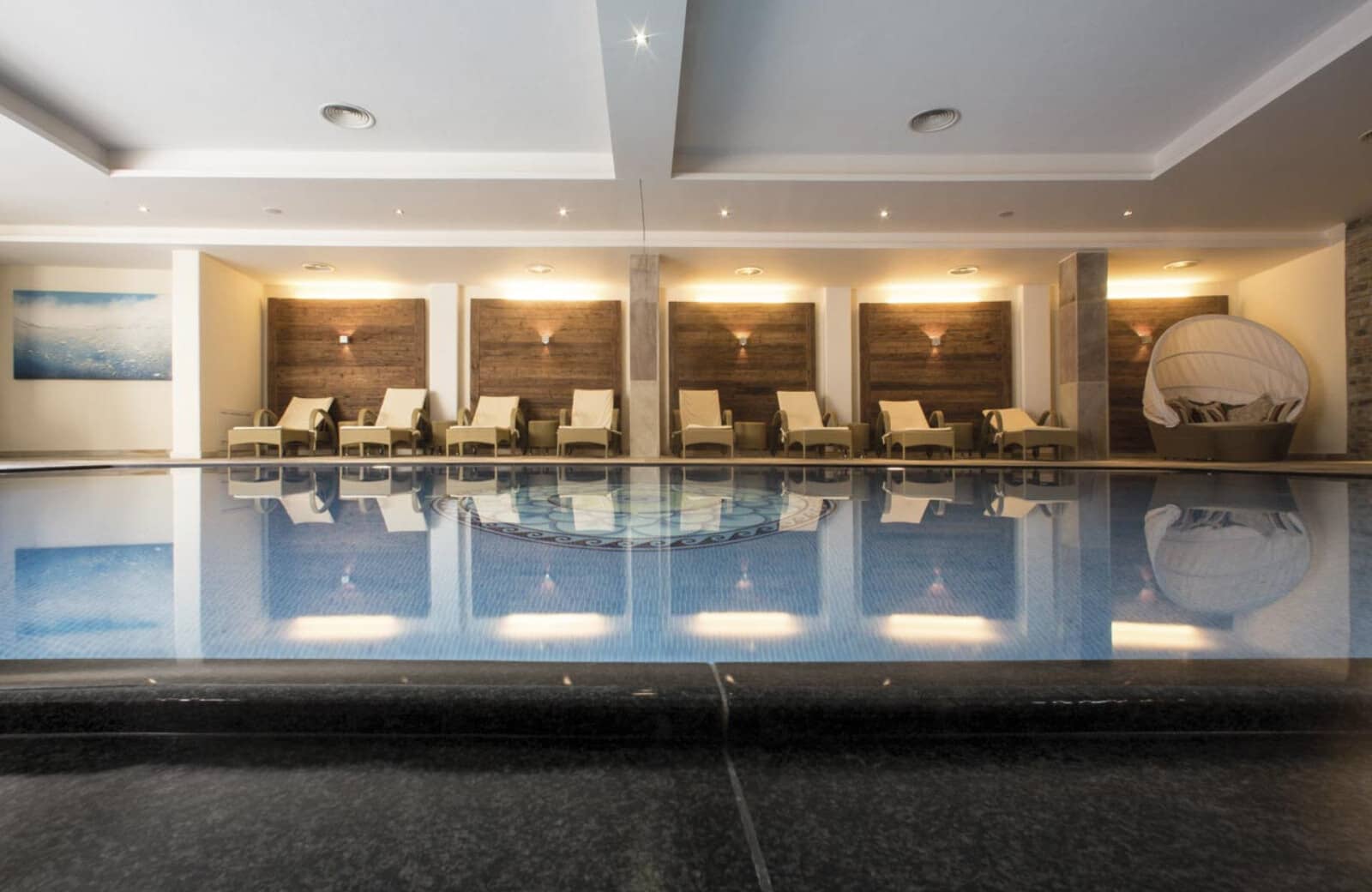 Indoor heated pool with loungers and mosaic tile floor detail
