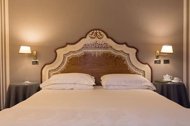King bed with ornate hand-painted headboard and bedside sconces