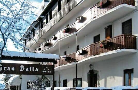 Hotel exterior featuring private wood-paneled balconies and snowy mountain setting