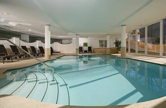 Indoor heated pool with poolside loungers and walk-in stairs