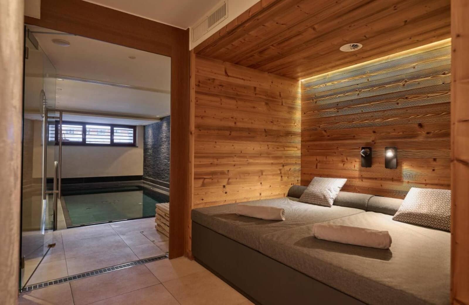 Spa relaxation area with wood-paneled daybed and indoor pool access