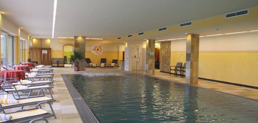 Indoor heated pool with poolside loungers and integrated massage jets