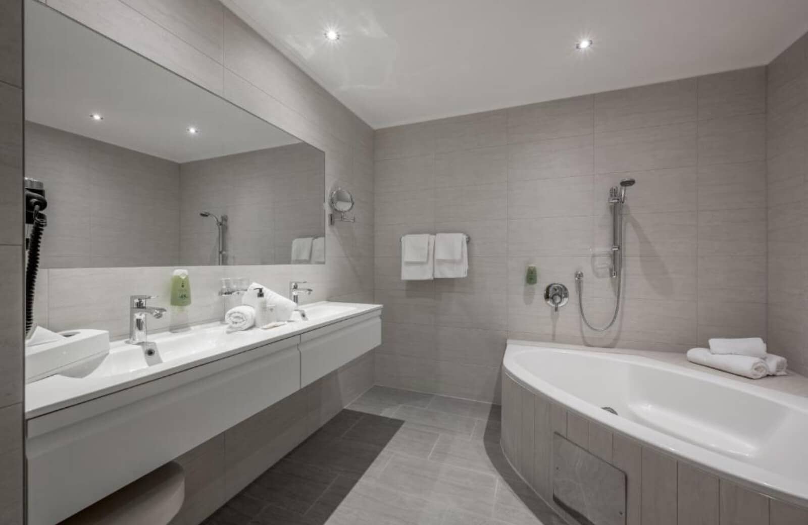 Bathroom with dual vanity, wide mirror, and deep soaking tub