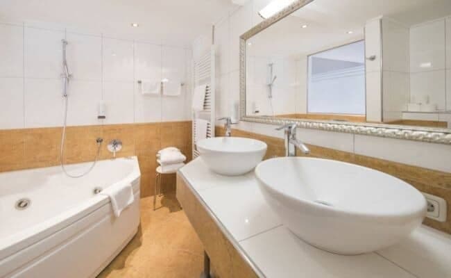 Bathroom with dual vessel sinks, jetted soaking tub, and heated towel rack