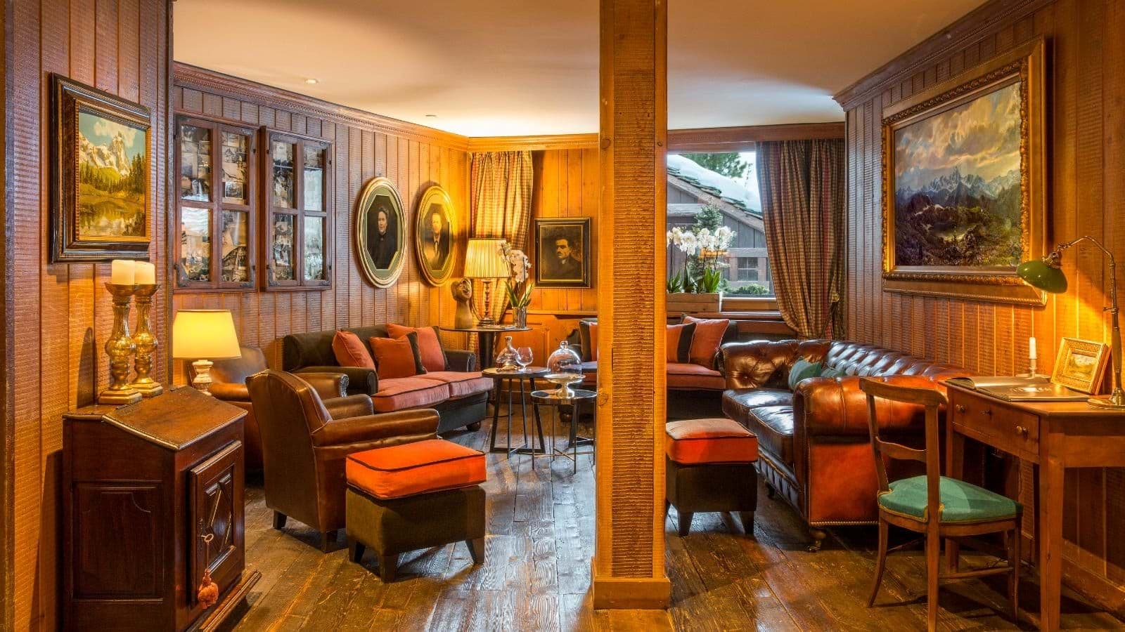 Wood-paneled lounge with leather seating and snowy mountain view