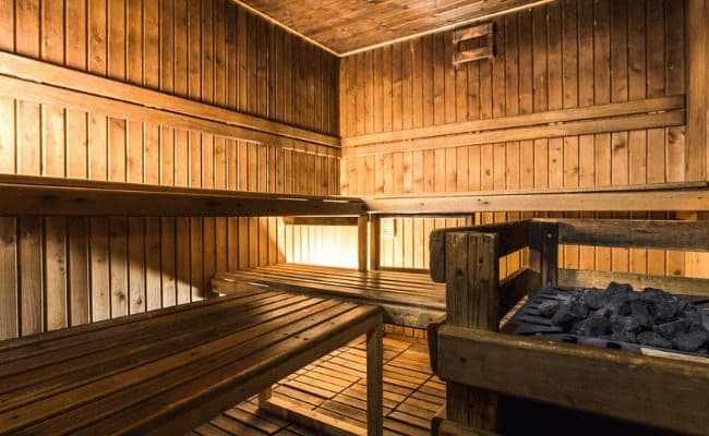 Private cedar sauna with tiered seating and electric rock heater