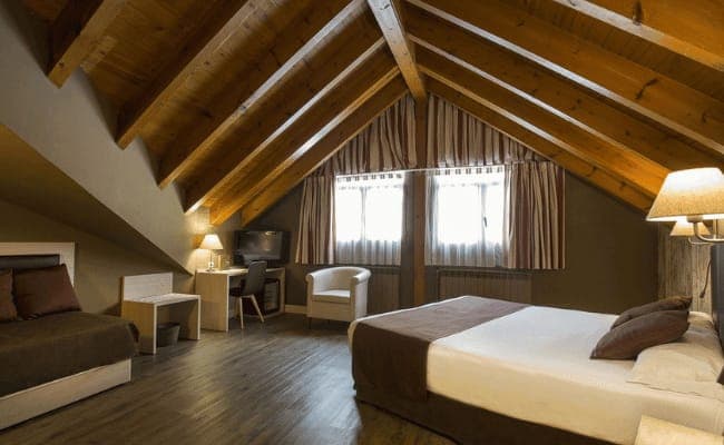 Attic bedroom with queen bed, dedicated workspace, and exposed timber beams